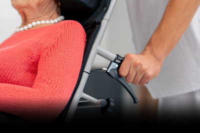 person assisting elderly woman in wheelchair