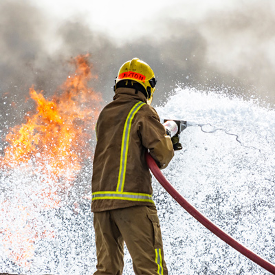 firefighter extinguishing flames with hose in action demonstrating fire safety techniques and rescue skills