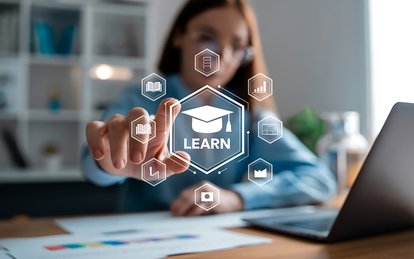 person interacting with digital learning icons while studying on a laptop in a modern workspace focused on education and technology learning tools for success