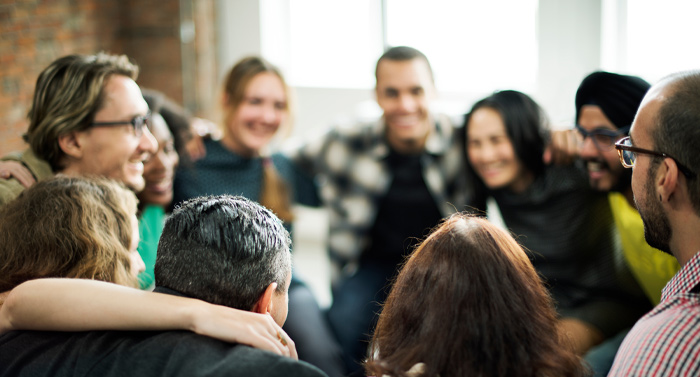 a group of diverse people sitting closely together laughing and enjoying a social gathering with positive interactions and engaging connections celebrating teamwork and friendship in a casual atmosphere