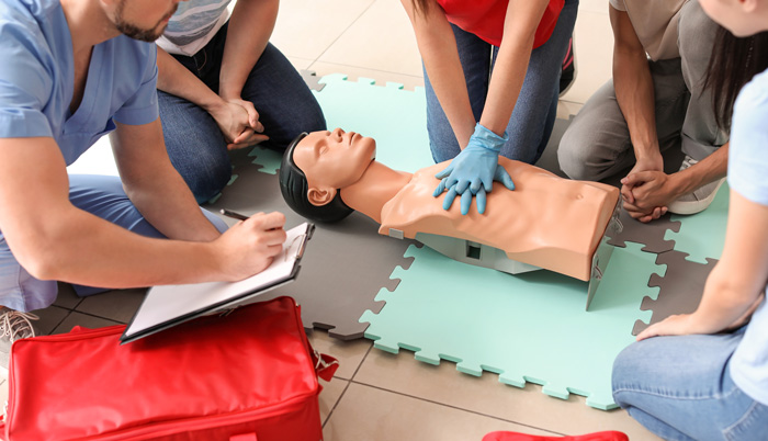 group practicing CPR techniques on a training mannequin with a medical bag nearby demonstrating lifesaving 4 methods for emergencies