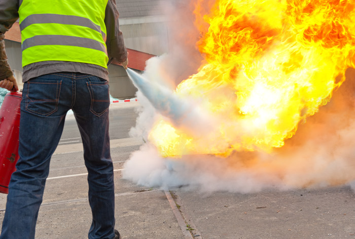 person wearing reflective vest using fire extinguisher to put out fire demonstrating fire safety techniques 2 safety measures 2 emergency response